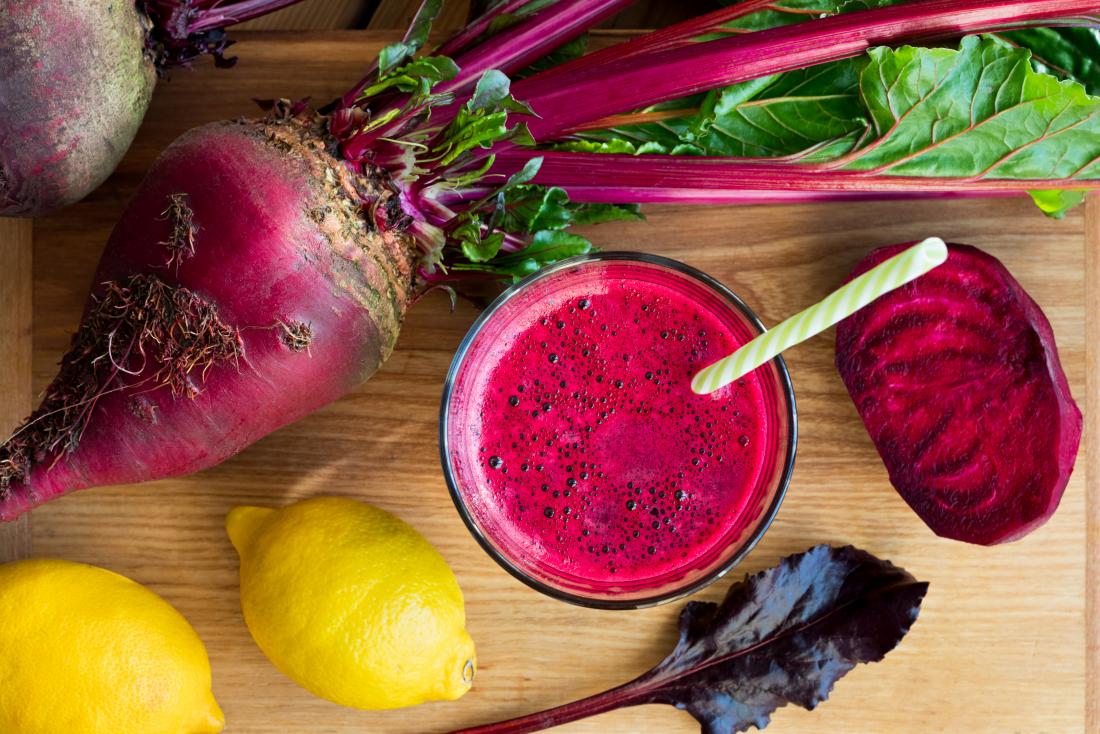 Beetroot juice in glass top down view with lemon and lettuce