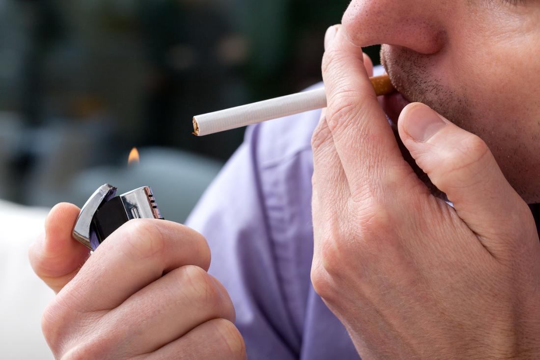 man using a lighter to light cigarette