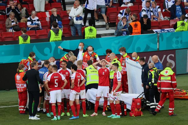 Denmark's players gather around teammate Christian Eriksen, who collapsed on the pitch during a match...