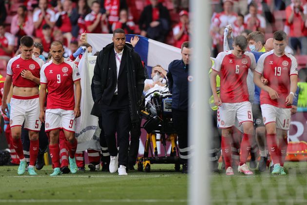 Denmark's players escort Eriksen off the