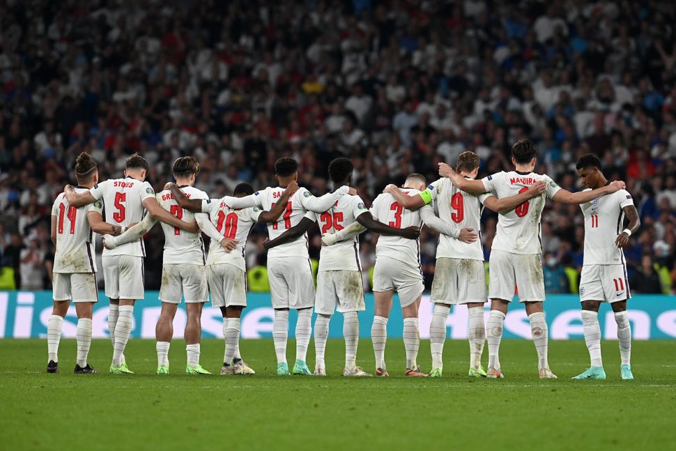 Players of England watch from the halfway line during the penalty shoot