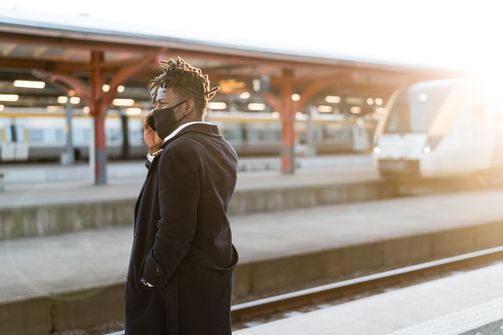 Handsome confident businessman on his way home from work. He is standing on the train station platform at sunset, waiting for his train.