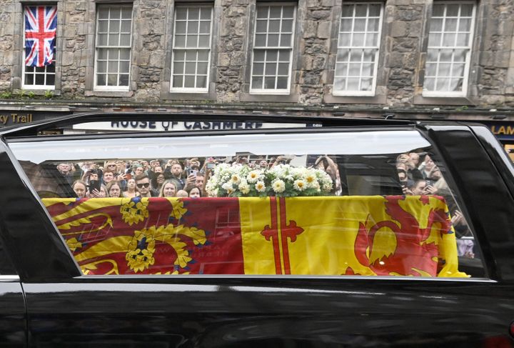 Members of the public watch the hearse carrying the coffin of Queen Elizabeth II as it is driven through Edinburgh.