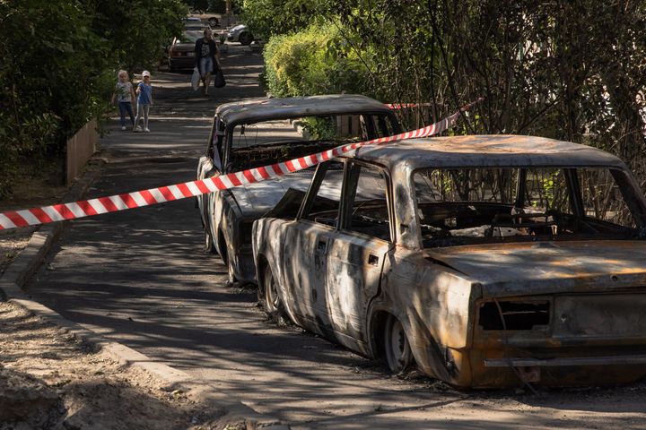 Children look at burned cars at the site where Russia's intercepted drone debris fell, on May 31, 2023 in Kyiv, Ukraine. 