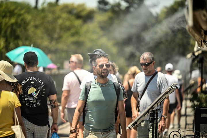 A man walks past misting fans of a shop in Athens, on July 13, 2023. Greece's national weather service EMY on July 10, 2023, said a six-day heatwave would grip Greece starting July 12. (Photo by SPYROS BAKALIS / AFP) (Photo by SPYROS BAKALIS/AFP via Getty Images)