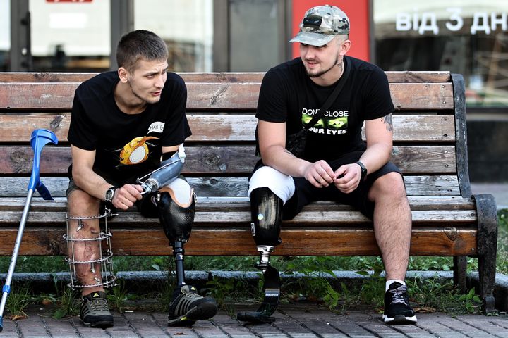 Ukrainian military veterans with amputations rest on bench on Khreshchatyk street in August in Kyiv, Ukraine.